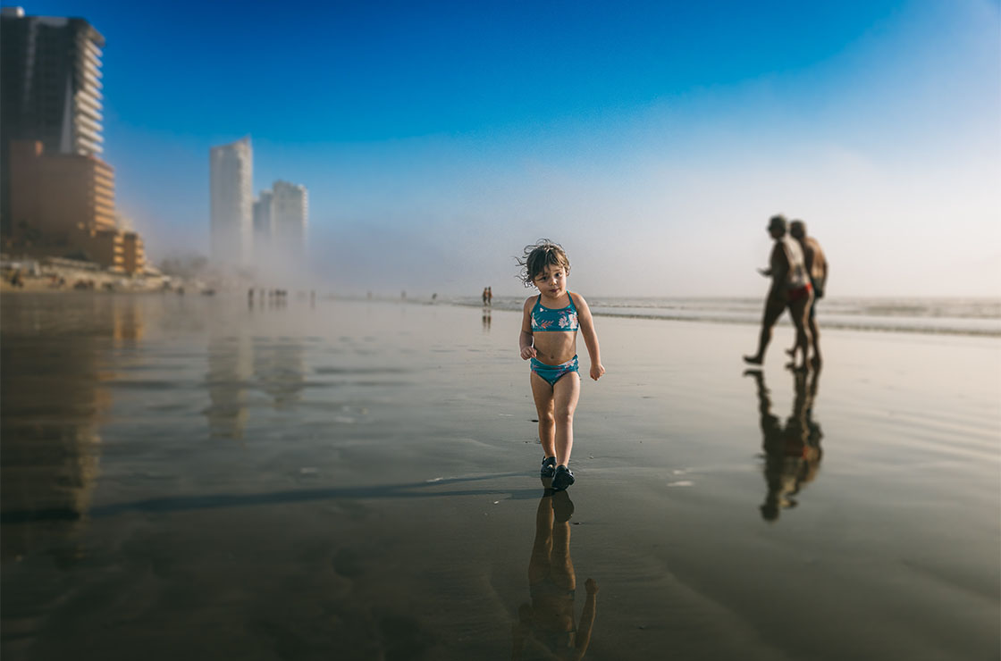 Young girl walks in the tide at the ocean